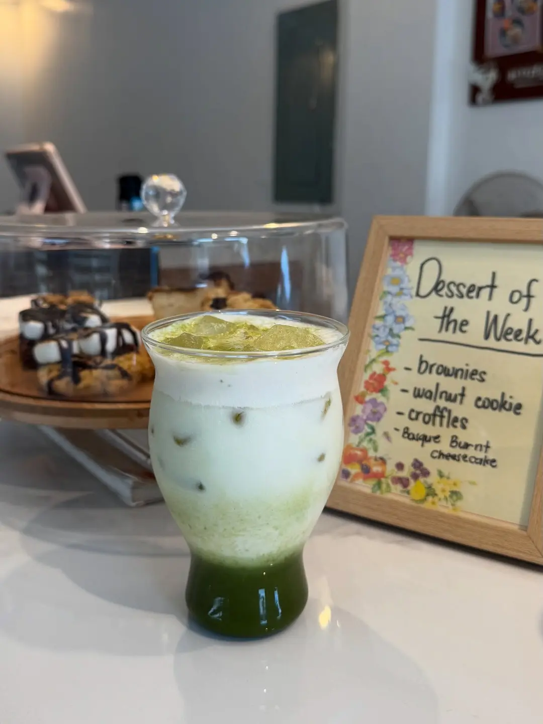 The dessert case beside a Dessert of the Week sign and an iced matcha