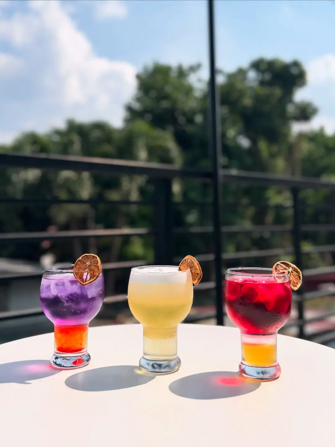 Three colorful iced drinks catching the last light on the terrace