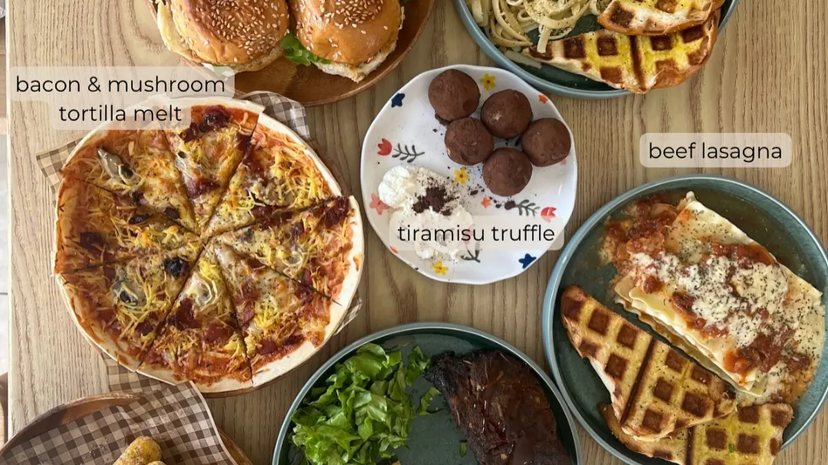 A table filled with café dishes: sliders, pasta, tortilla melts, lasagna and desserts