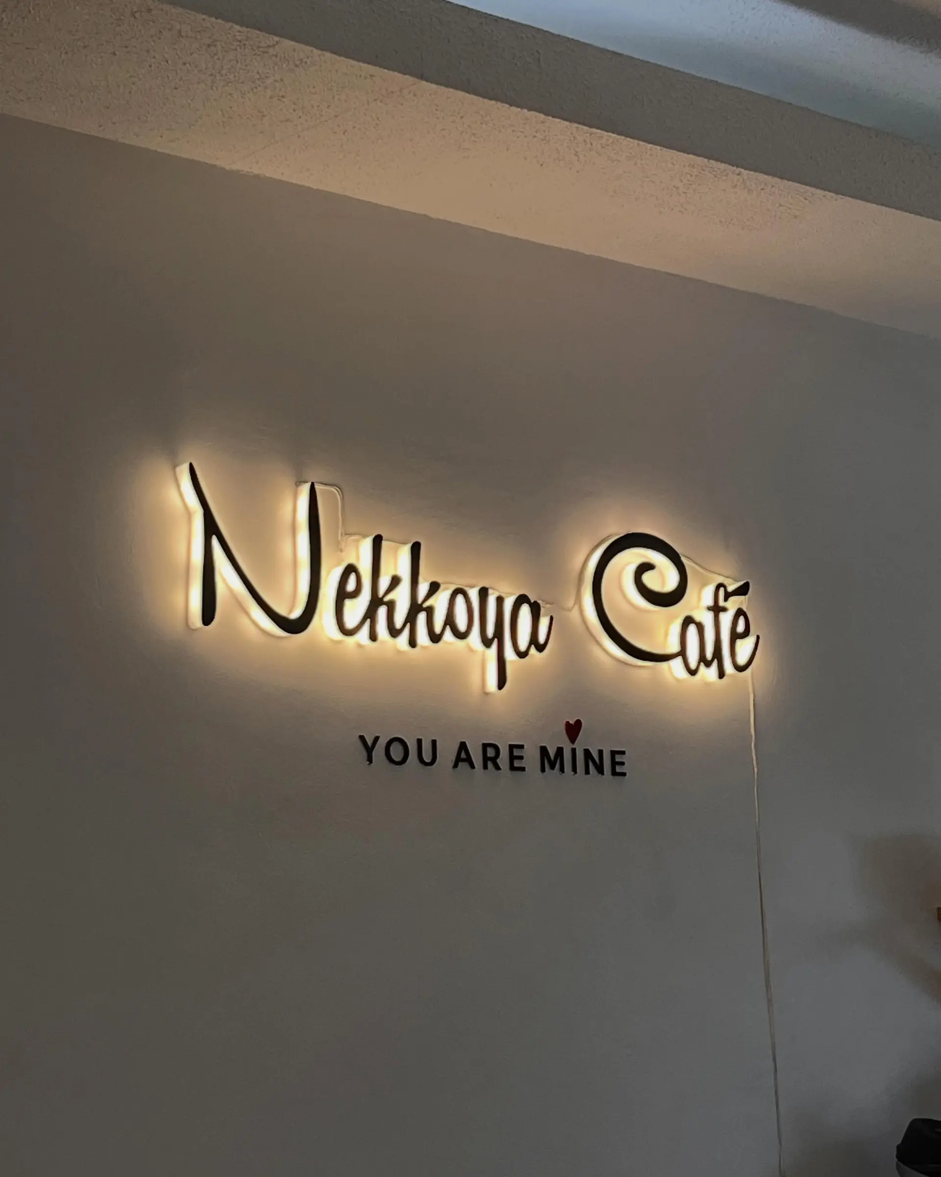 Backlit Nekkoya Café signage — You Are Mine — glowing warm on the wall