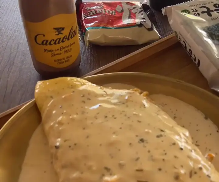 A cheese-sauced buldak omelette on a gold plate