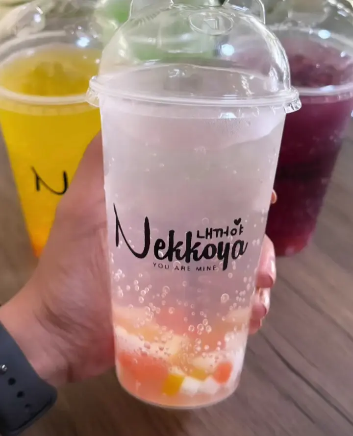 A hand holding a Nekkoya fruit soda with two more behind